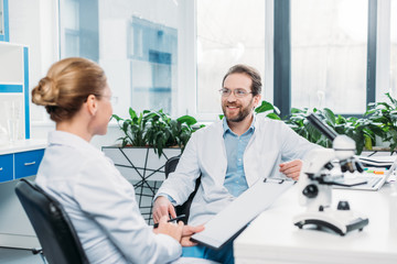 Wall Mural - scientists in lab coats and eyeglasses discussing work at workplace in lab