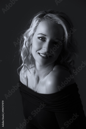 Beautiful Blond Woman In Curly Hair And Black Top On Grey