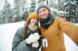 © pressmaster - Happy young dates in winterwear making selfie in winter forest