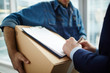 © pressmaster - Receiver signing delivery document on top of unpacked box held by courier