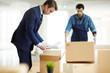 © pressmaster - Businessman in suit taking out business papers from open box while working in new office area