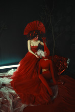 Beautiful Model Wearing Red Dress And Crown Is Posing In A Dark Surreal Studio
