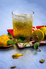 Close up of INDIAN popular summer drink JAGGERY SHRABAT/gud ka shrabat with all its ingredients i.e. lemon,ginger juice, soaked sweet basil, some mint leaves & Jaggery/gud.