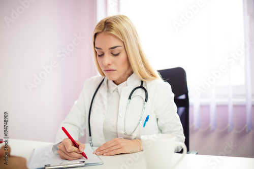 Fotografie, Obraz Female doctor writing down some information about her patient.