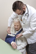 Lekarz w białym fartuchu zakłada temblak na rękę bardzo starej kobiety.