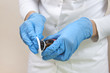 Pielęgniarka w niebieskich jednorazowych rękawiczkach nasącza wacik w płynie do dezynfekcji ran.