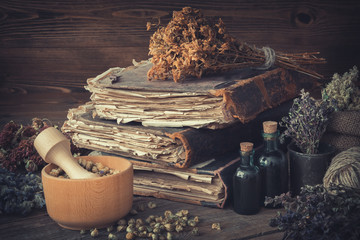 Wall Mural - Tincture bottles, bunches of dry healthy herbs, stack of antique books, mortars, sack of medicinal herbs. Herbal medicine.
