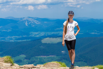 Young happy woman on the top of the hill enjoy beautiful view of sky and mountains, freedom and harmony concept