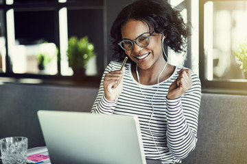 Wall Mural - Smiling young African woman chatting online with her laptop