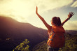 © lzf - happy woman backpacker looking at the view  with arms outstretched on mountain top during sunrise