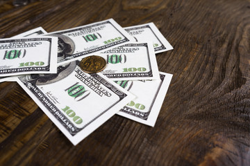 Fan of hundred dollar bills and one dollar coins on a wooden background