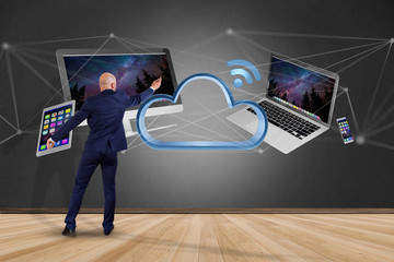 Poster - Businessman in front of a wall with Devices like smartphone, tablet or computer flying over connected cloud - 3d render