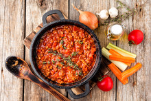 Classic Italian Bolognese Sauce Stewed In Cauldron With Ingredients On Wooden Table, Top View