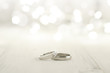 Two wedding rings place on wooden floor with light bokeh background.
