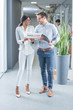 © Bojan - Full length portrait of two smiling business people with documents talking in office hallway.