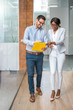 © Bojan - Happy business people walking through office hallway and discussing papers.
