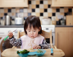 Wall Mural - Baby girl eating messy at home kitchen