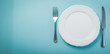 Intermittent fastin concept - empty plate on blue background