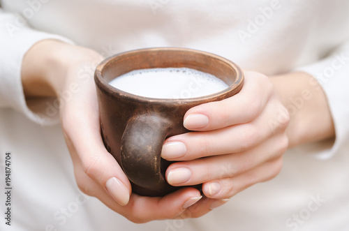 Zdjęcie XXL Świeży mleko w glinianej filiżance w żeńskich rękach