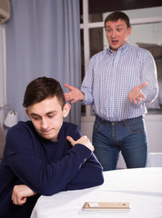 Adult man is asking forgiveness from his sad son after conflict