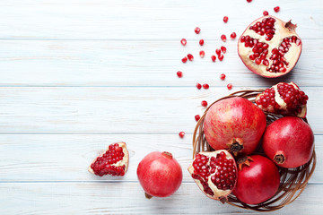 Poster - Ripe and juicy pomegranate in basket on wooden table