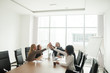 © fizkes - Happy business people giving high five building successful team in office sitting at meeting table, multiracial motivated group celebrating victory join hands together, unity help support in teamwork