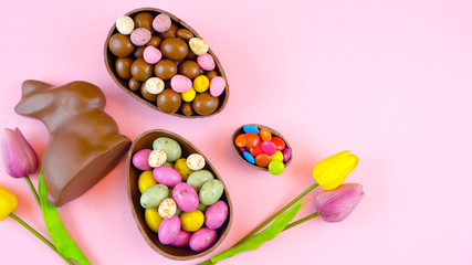 Wall Mural - Happy Easter overhead with chocolate Easter eggs and decorations on a wood table background