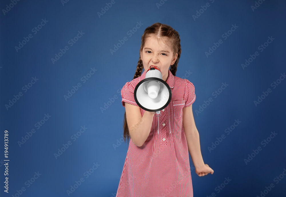 Emotional little girl shouting into megaphone on color background