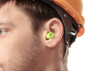 Wall Mural - Male worker with earplug on white background. Hearing protection equipment