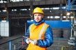 © Seventyfour - Waist-up portrait of handsome young worker wearing uniform and hardhat looking at camera while holding digital tablet in hands in order to operate machine at production department of modern plant.