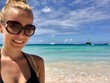 Beautiful blonde woman in Barbados wearing a bikini at a untouched beach with crystal clear turquoise water and a blue sky