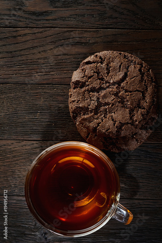 Zdjęcie XXL Szklany teacup z czekoladowych układów scalonych ciastkami na bawełnianej pielusze na nieociosanym drewnianym tle, odgórny widok