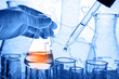 © totojang1977 - Flask in scientist hand with laboratory glassware background