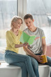 © LIGHTFIELD STUDIOS - happy girlfriend showing book to boyfriend at home
