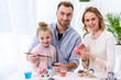 © LIGHTFIELD STUDIOS - Child and parents coloring eggs for Easter
