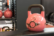 Old And Used Big Pink Kettlebell On A Bench In A Gym. Gym And Fitness Equipment.
