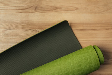 Canvas Print - top view of green rolled yoga mat on wooden floor