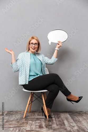 Smiling business woman holding speech bubble. Poster