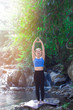 porty young woman doing yoga practice with stream and forest background - concept of healthy life and natural balance between body and mental development