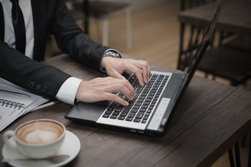 Poster - Young Asian businessman working with a laptop in a coffee shop.