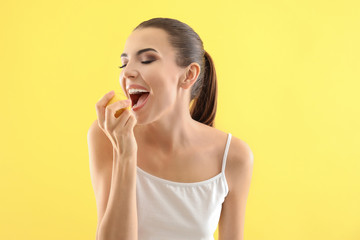 Poster - Beautiful young woman eating ripe lemon on color background