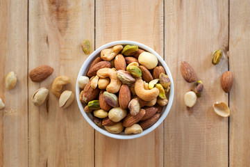 Poster - Healthy food and snack : mixed nuts in white ceramic bowl from above,  Walnut, pistachios, almonds, hazelnuts and cashews..