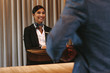 © Jacob Lund - Smiling hotel receptionist attending guest at check-in counter