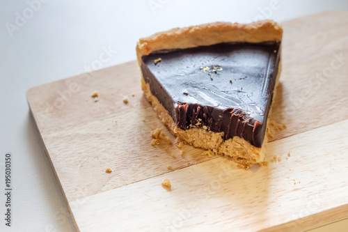 Zdjęcie XXL Kawałek chrupiącego tortu czekoladowego z ukąszeniem na drewnianej płycie z dziennym korytem w oknie kuchni.
