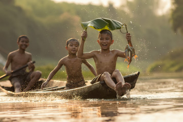 asia children enjoying in boat on beautiful river