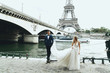 © syrotkin - Luxury wedding couple poses before river Seine and the Eiffel Tower somewhere in Paris
