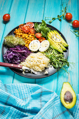 Wall Mural - Healthy vegan lunch bowl. Vegan buddha bowl. Vegetables and nuts in buddha bowl on blue wood background.