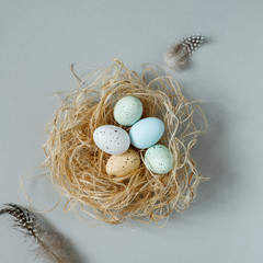 Wall Mural - Happy easter. Easter eggs in nest with easter decoration, top view