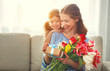 happy mother's day! child daughter   gives mother a bouquet of flowers to tulips and gift.