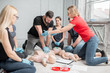 © rh2010 - Young woman instructor helping to make first aid heart compressions with dummy during the group training indoors